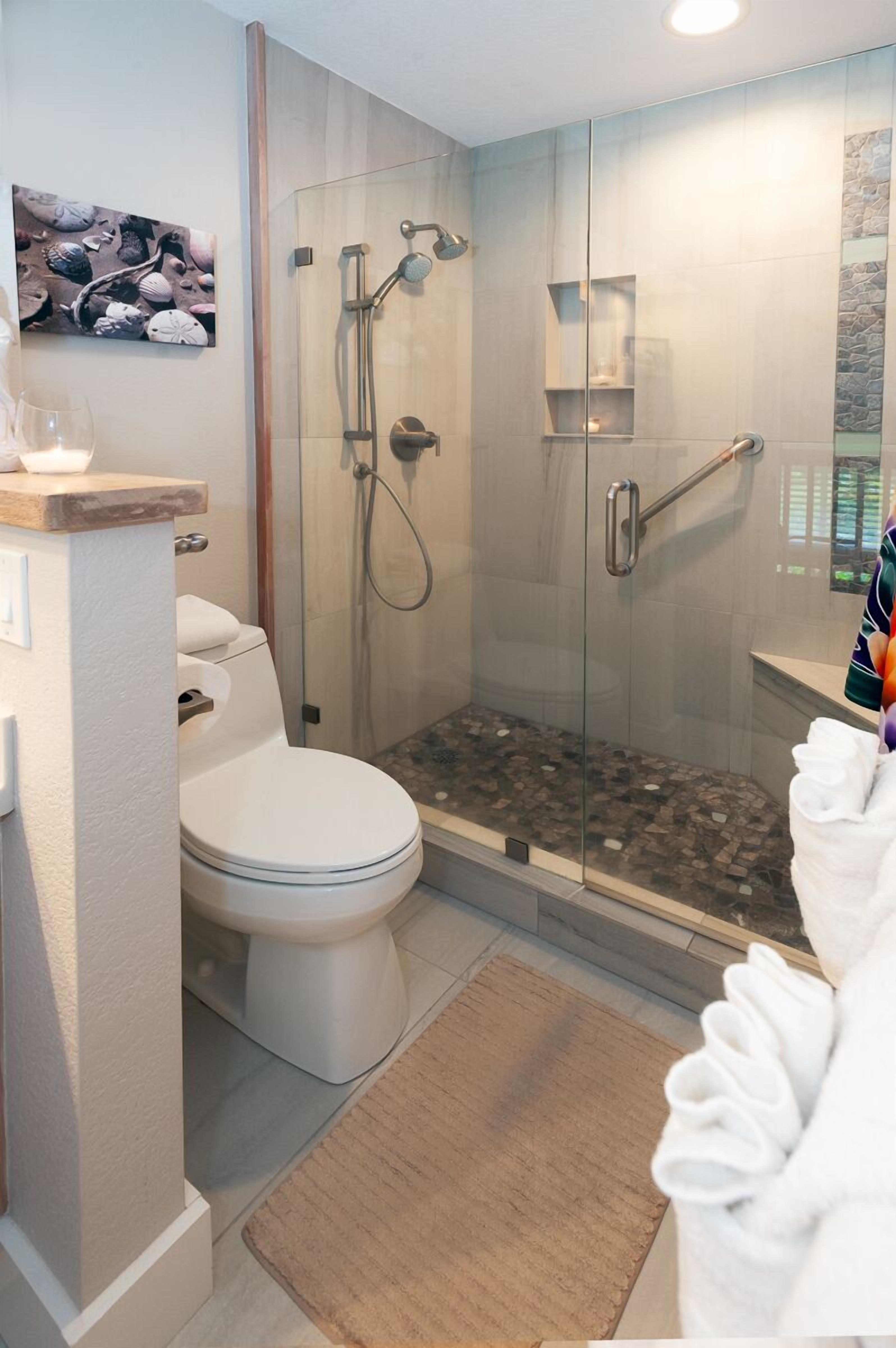 A modern bathroom with a glass-enclosed shower, a toilet, and a sink.