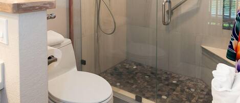 A modern bathroom with a glass-enclosed shower, a toilet, and a sink.