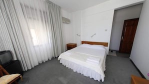 A hotel room with a large bed, a TV, a wooden chair, and a desk. - Mer Pansiyon (Fethiye)
