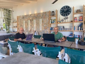 Two men seated at a table with laptops, surrounded by bookshelves and decorative items. - Villa Eleni Corfu: Seaview, Pool, Sleeps 10-20, Near Beach & Village! 🌊🏡 (Acharavi)