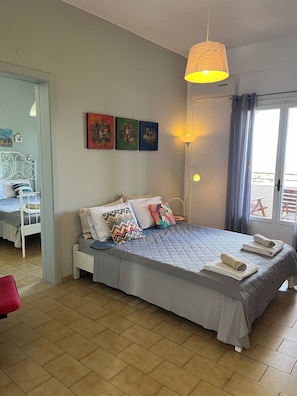 A bedroom with a bed, a desk, and a chair. There are three paintings on the wall. - Villa Eleni Corfu: Seaview, Pool, Sleeps 10-20, Near Beach & Village! 🌊🏡 (Acharavi)