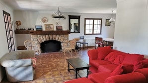 A living room with a stone fireplace, a red sofa, striped armchairs, and a wooden coffee table. - Villa for 8 people, private pool villa with unobstructed views, Bagnols-en-F, beautiful location (Bagnols-En-Forêt)