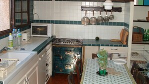 A kitchen with a stove, sink, and various kitchen utensils. There is a dining table with chairs and a vase of flowers. - Villa for 8 people, private pool villa with unobstructed views, Bagnols-en-F, beautiful location (Bagnols-En-Forêt)