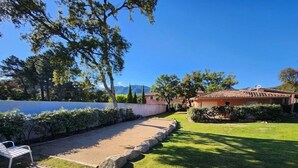 A residential property with a well-maintained lawn, a patio area, and a house with a tiled roof.