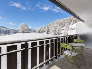 A balcony with a metal railing, two green chairs, and a table.