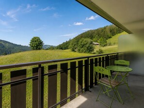 A balcony with a view of a green landscape, a wooden bench, and two green chairs. - Studio on ski trails, pets allowed (La Clusaz)