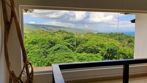 Un balcone con vista su dolci colline verdi e una costa lontana.