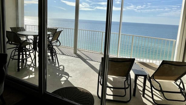 Un balcon avec vue sur l’océan, aménagé avec des chaises et une table.