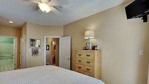 A bedroom with a bed, a ceiling fan, a dresser, and a television. - Tybee Sands 4A | Steps to Beach, Dining, Shops (Tybee Island)