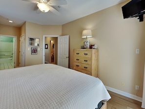 Un dormitorio con cama, ventilador de techo, cómoda y televisor.