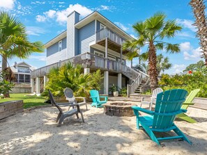Une propriété située en bord de mer, comprenant un bâtiment à deux étages, un espace extérieur aménagé avec des chaises et un foyer.