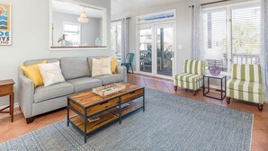 A living room with a grey sofa, a wooden coffee table, a striped armchair, and a small table with a vase. - Beach Digs | Bay View, Heated Pool, Steps to Beach (Tybee Island)