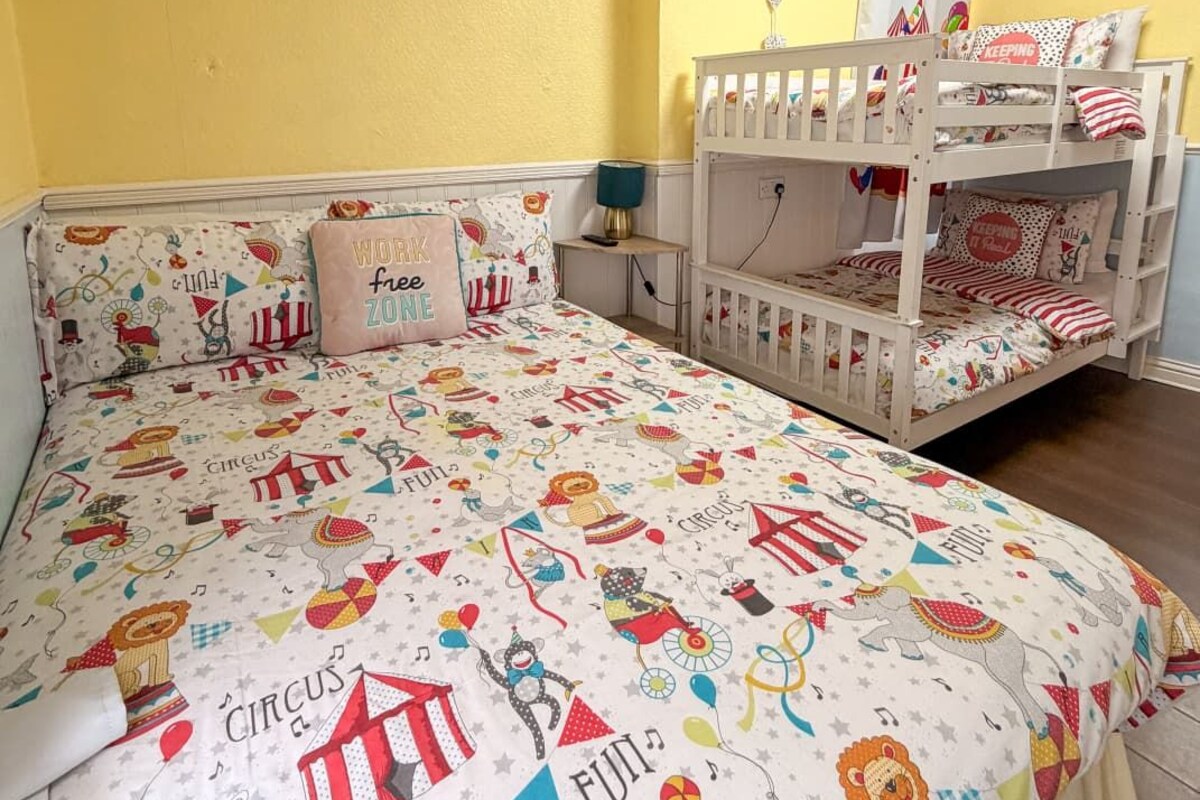 A child's bedroom with a bunk bed, a bedside table with a lamp, and a wall with a painting.