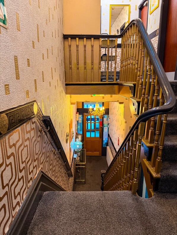 A grand staircase with ornate railings and a patterned wall, leading to a well-lit entrance area. - OYO Wynnstay Hotel (Blackpool)