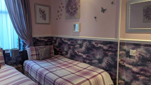 Un dormitorio con dos camas, una ventana con cortinas, decoración en la pared y un cabecero decorativo.