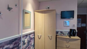 Una habitación con un armario de madera, un televisor montado en la pared y un revestimiento mural con diseño de mármol.