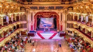 Un teatro majestuoso con arquitectura ornamentada, un escenario central y varios palcos.