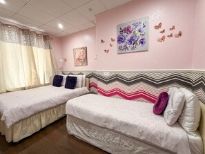 A bedroom with two beds, a decorative wall with butterfly stickers, and a floral painting. - OYO Wynnstay Hotel (Blackpool)