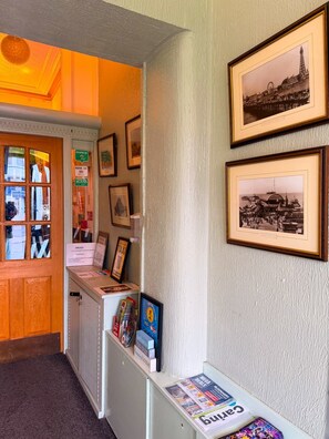 A reception area with framed pictures, a counter with informational brochures, and a door with windows. - OYO Wynnstay Hotel (Blackpool)