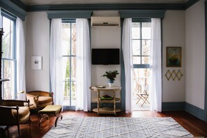 Una sala de estar con televisor, una mesa redonda de madera, un sofá y un tapete estampado.