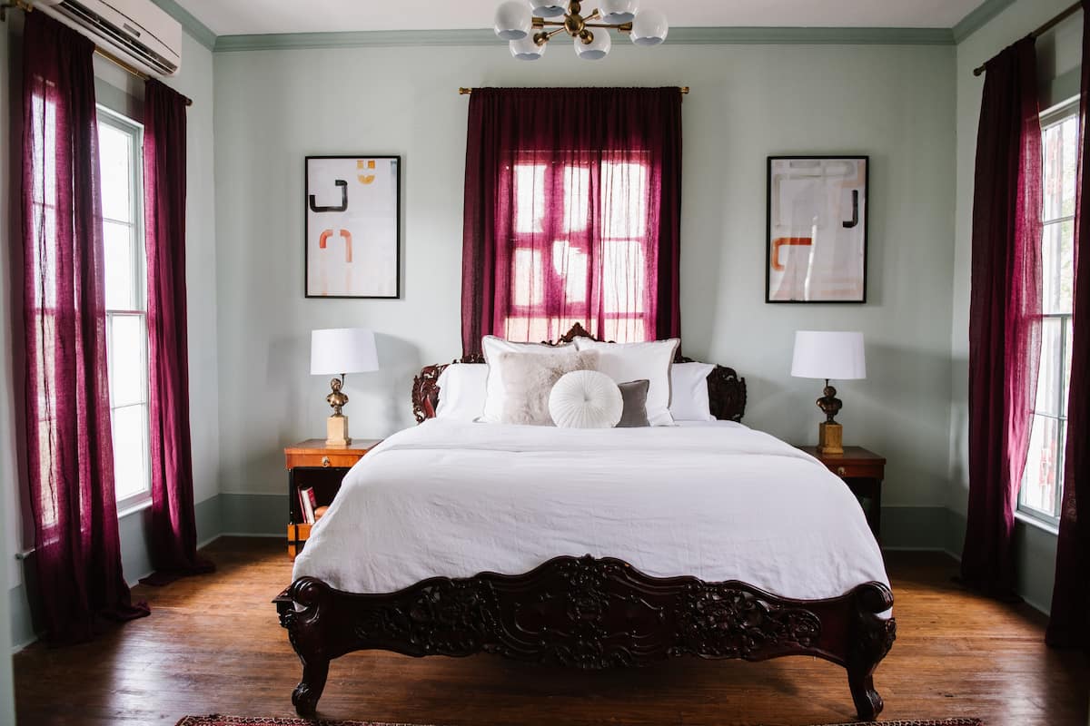 A bedroom with a large bed, two bedside tables, and a window with curtains.