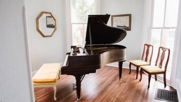 A grand piano in a room with hardwood floors, a bench, and two chairs.