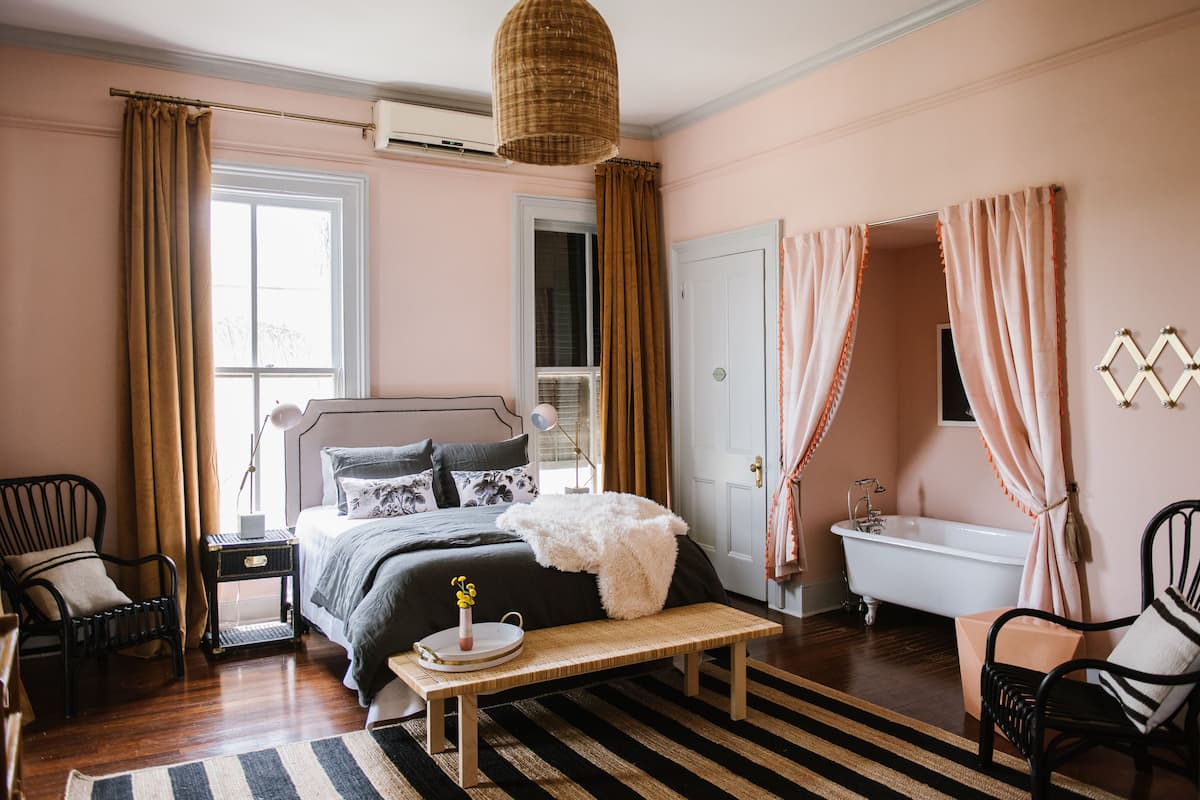 A bedroom with a bed, bedside table, lamp, and a view of the bathroom.