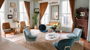 A well-lit living room with leather chairs, a round coffee table, and a fireplace. - Carr Mansion (Galveston)