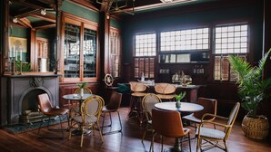 A cozy room with a fireplace, wooden furniture, and large windows. - Carr Mansion (Galveston)