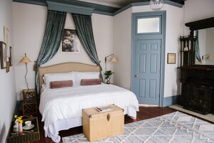 Une chambre à coucher avec un lit, une porte bleue, une commode et un miroir.