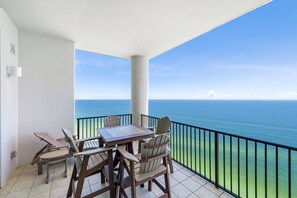 A balcony with a table and chairs, overlooking a body of water.