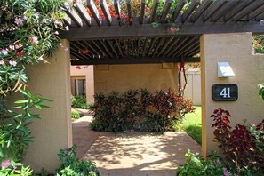 A covered entrance with a number 41 sign, surrounded by lush greenery and a wooden pergola.