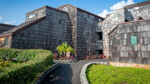A building with a wooden exterior and a pathway leading to the entrance. - Oceanfront and updated, top floor, perfect for honeymoon (Princeville)