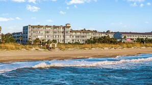 A beachfront hotel with multiple floors, balconies, and a beach view. - Beach House 413 | Oceanfront, Pet Friendly, Pools (Tybee Island)