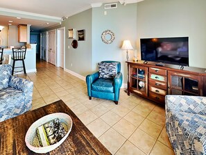 A living room with a TV, a blue armchair, and a patterned sofa.