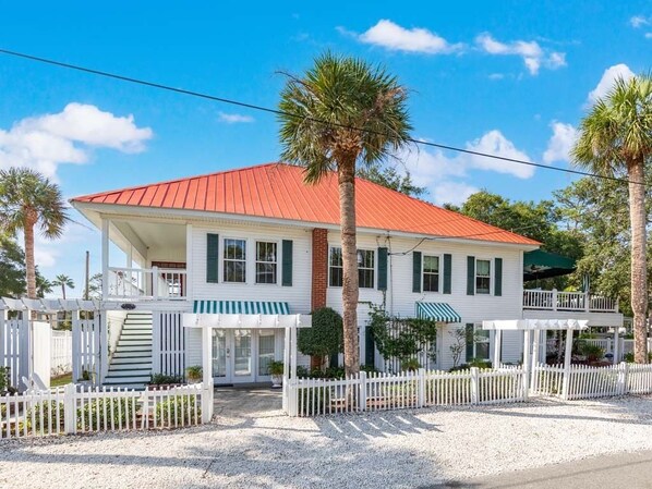 A two-story house with a red roof, white exterior, and a covered porch. - Tybreeza A | Apartment, Shared Pool, Near Beach! (Tybee Island)