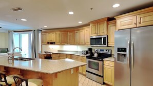 A modern kitchen with granite countertops, stainless steel appliances, and wooden cabinets. - Tybee Beach Club 137 | Condo Overlooking Beach! (Tybee Island)