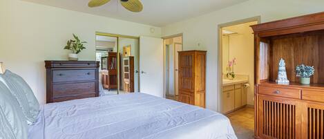 A bedroom with a bed, dresser, wardrobe, and a ceiling fan.