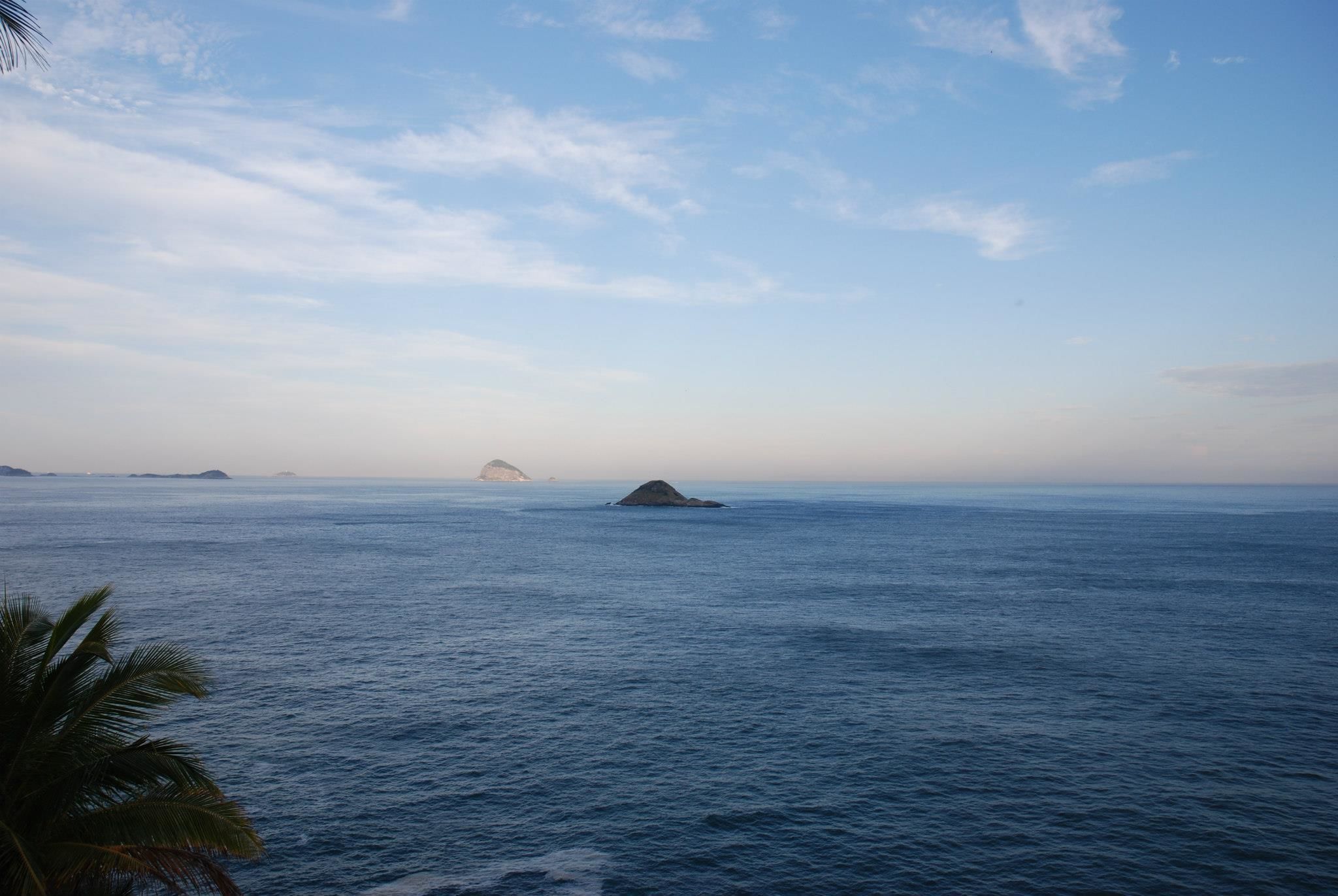 Mare calmo con isole in lontananza sotto un cielo sereno.