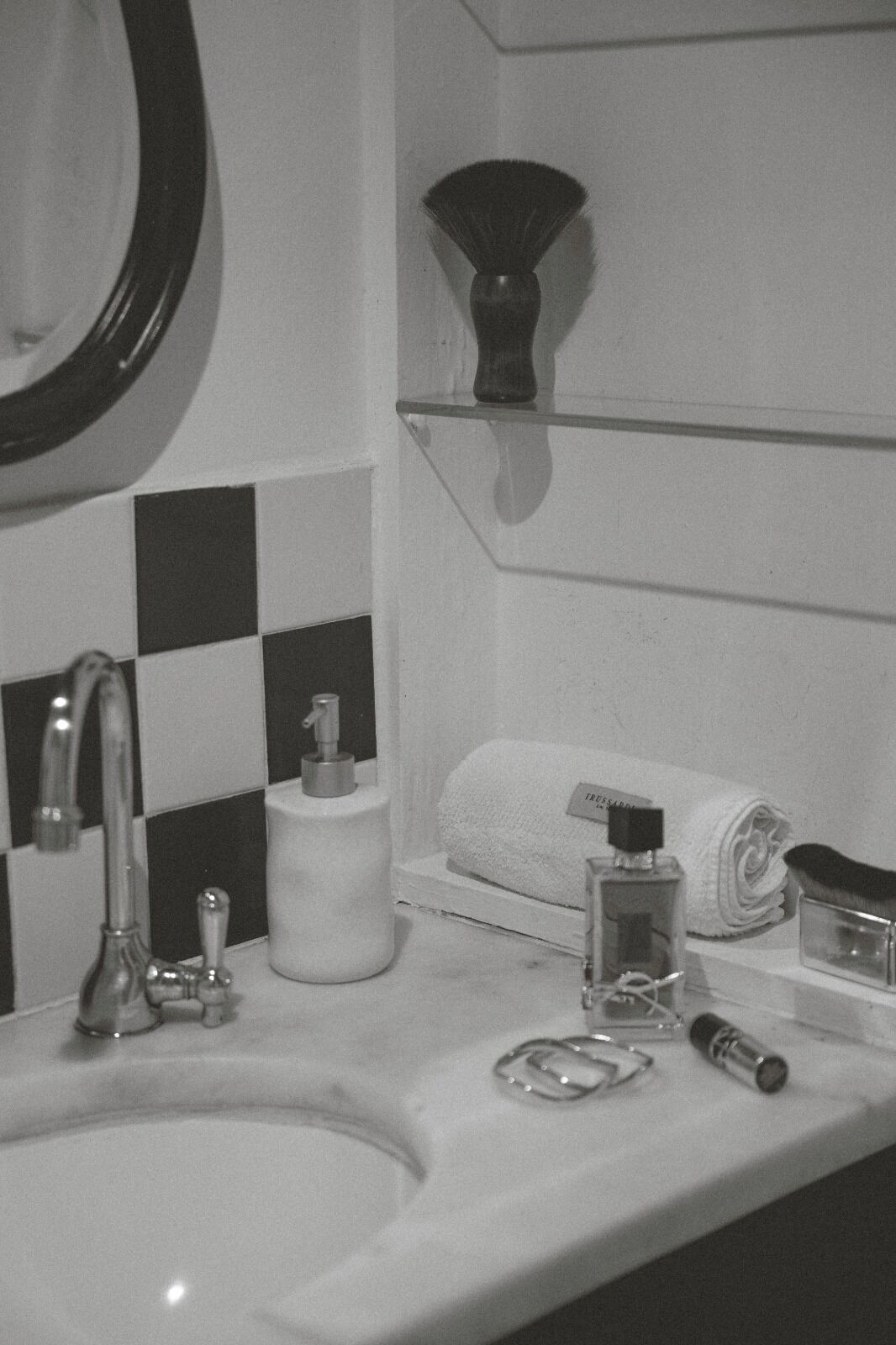A bathroom with a sink, mirror, and shelves with toiletries.