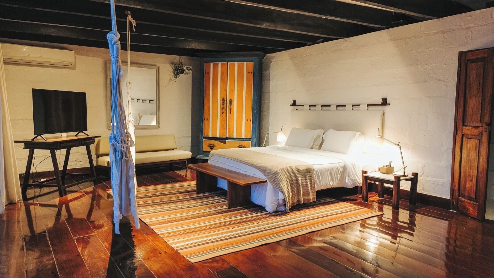 Una camera da letto con un letto, un comodino, una lampada e una panca in legno.