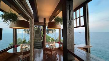A room with a view of the sea, a round table, and wooden furniture.