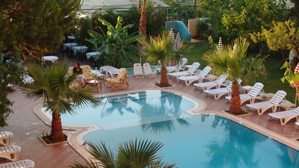A pool area with lounge chairs and palm trees. - Hotel Olivia (Kusadasi)