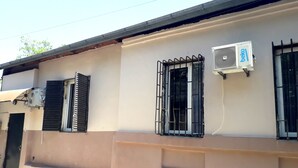 A building with two windows, one with a metal grill and the other with a metal grille. There is an air conditioning unit on the wall. - Gnt Plus (Tbilisi)