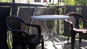 A balcony with two chairs and a table, overlooking a cityscape with buildings and greenery. - Gnt Plus (Tbilisi)
