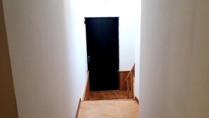 A narrow hallway with wooden parquet flooring and white walls. - Gnt Plus (Tbilisi)