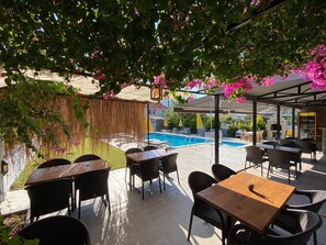 Un patio al aire libre con piscina, mesas y sillas.