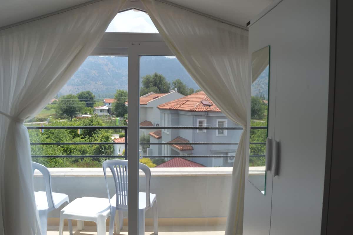 A balcony with white curtains, a table, and two chairs.