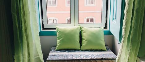 Asiento junto a la ventana con un cojín estampado y una almohada verde.