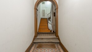 Un couloir étroit avec un escalier en bois menant à un palier.